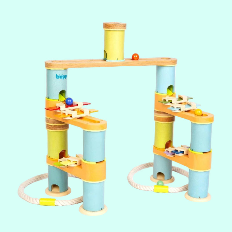 Colorful marble run toy set with wooden tracks and cylindrical platforms on a white background